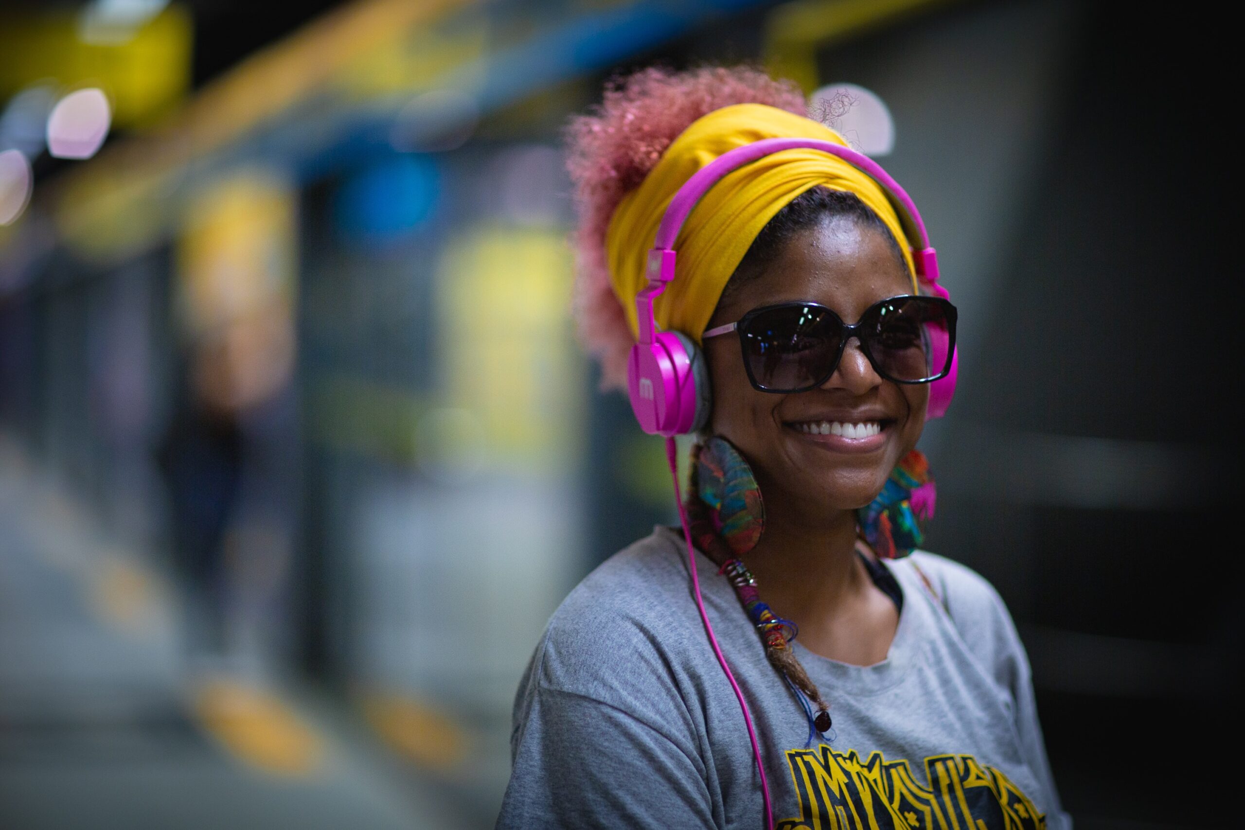 A black woman with pink earphones on a street